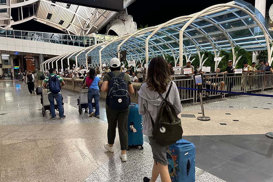 Travelers with suitcases at Denpasar airport arrivals